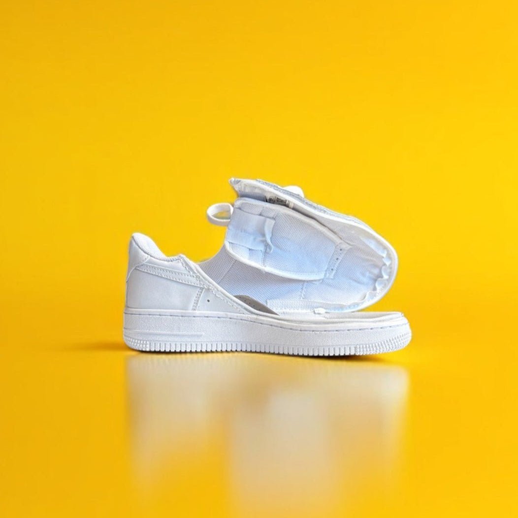 A white shoe with a zipper on a yellow background. The shoe is fully open