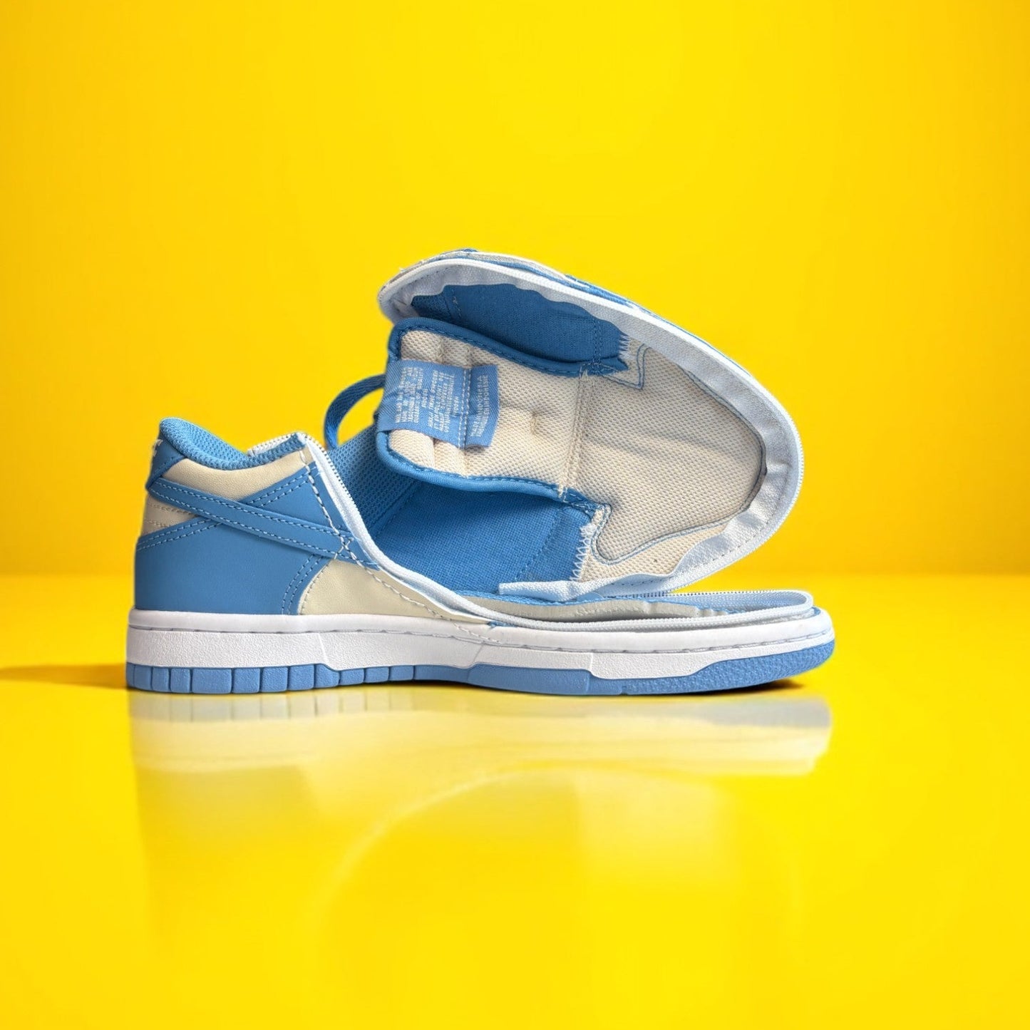A pair of Kids' shoes with a zipper, primarily in blue and white colors on a yellow background. The shoe is fully open