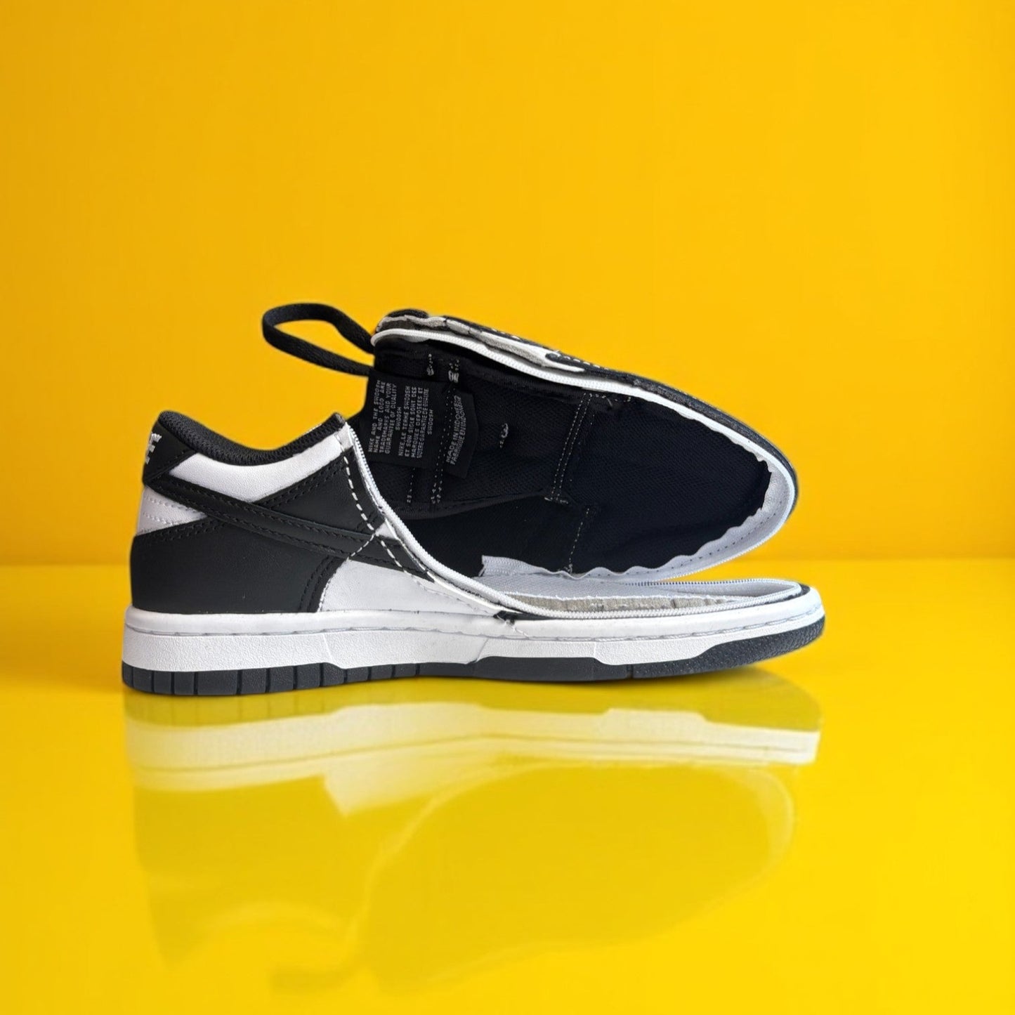 A pair of kids white and white shoes with a zipper. The shoe is fully open