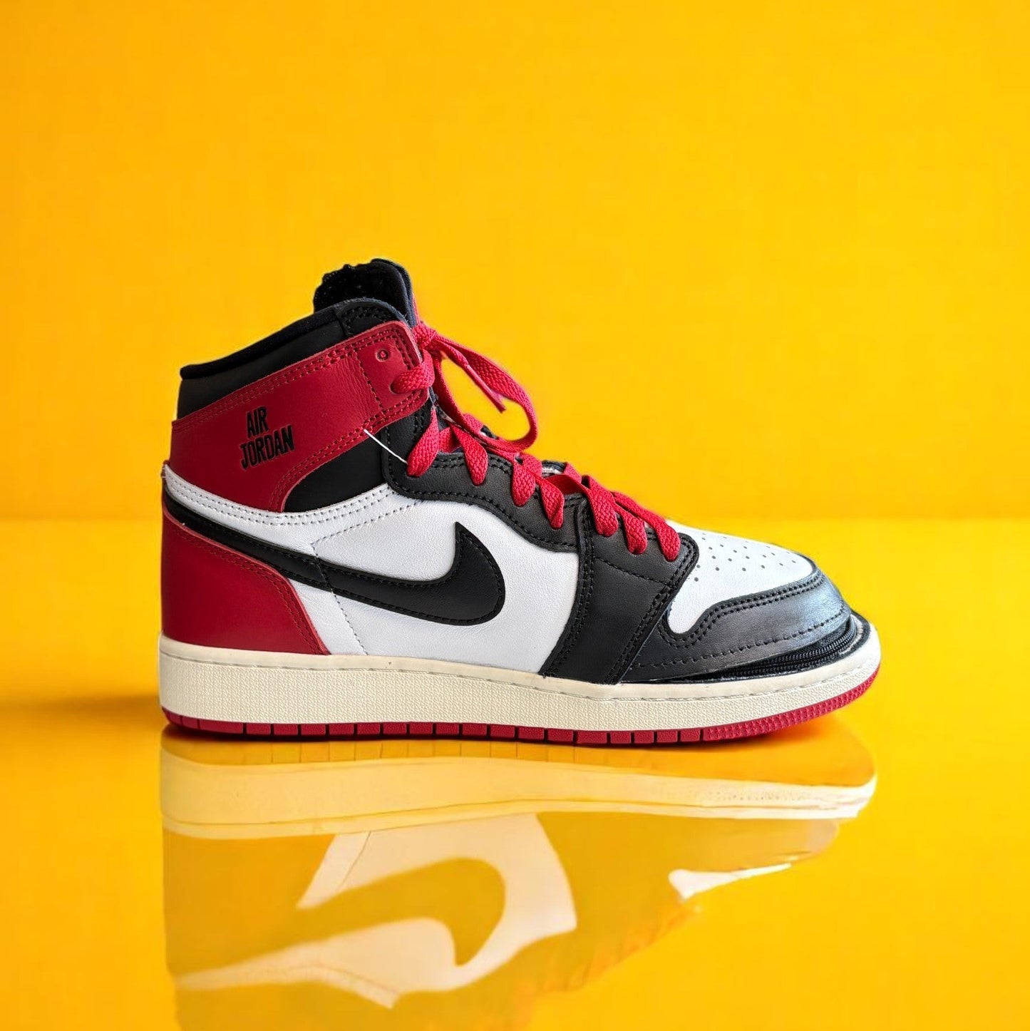 Black, white, and red shoe with a zipper. The zipper wraps around the shoe allowing it to open fully. The shoe is zipped shut