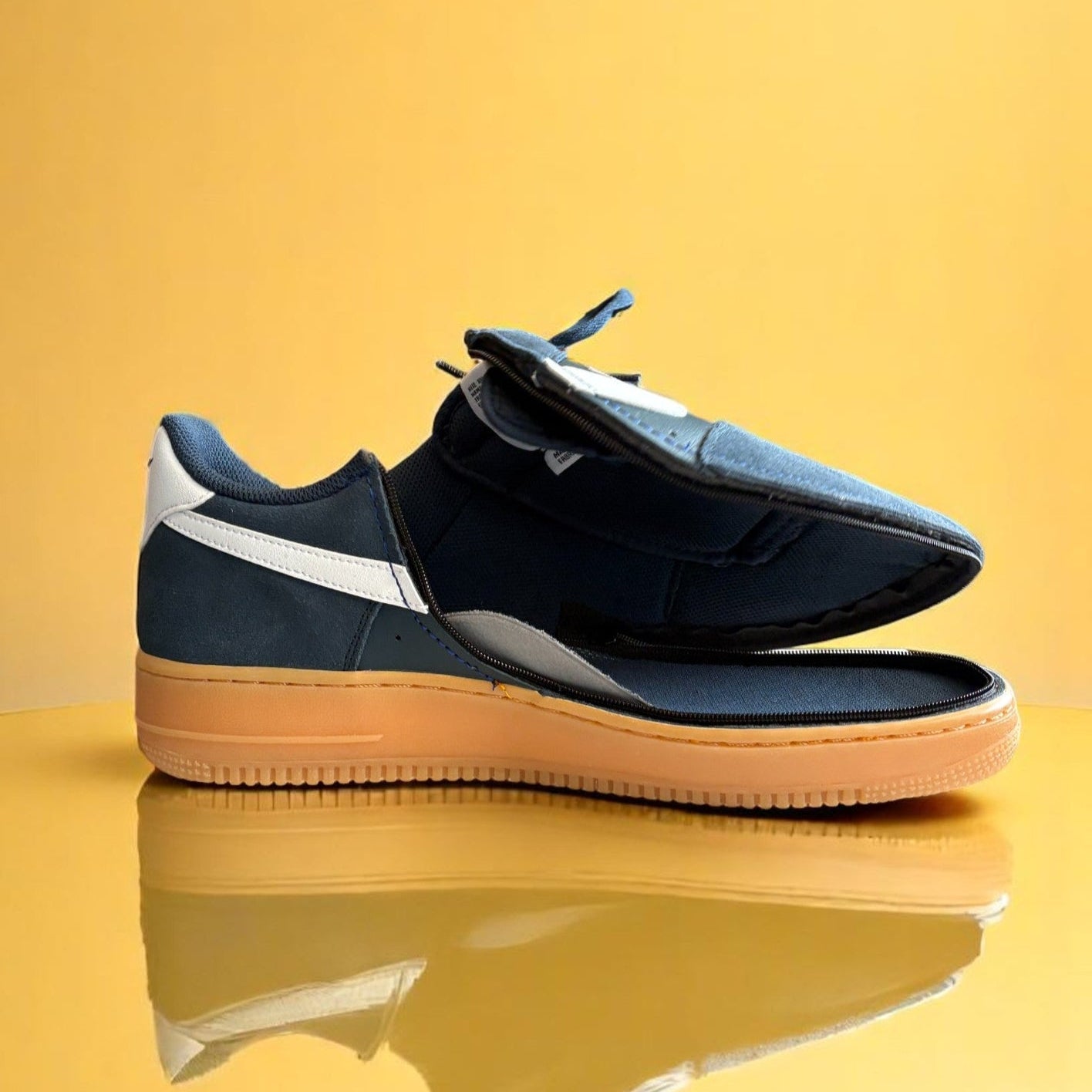 Navy blue shoe with a zipper on a yellow background. The shoe is fully open
