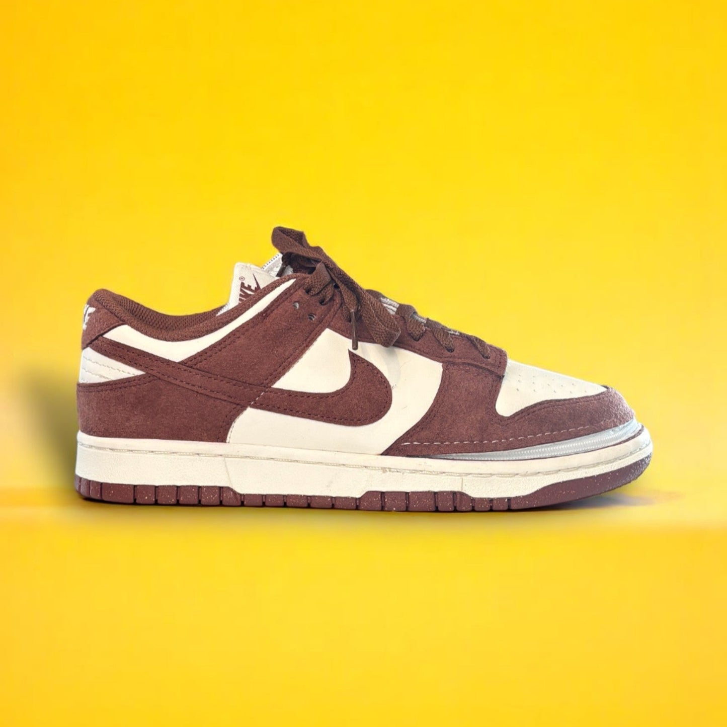 Maroon and white shoe with a zipper on yellow background. The shoe is zipped shut