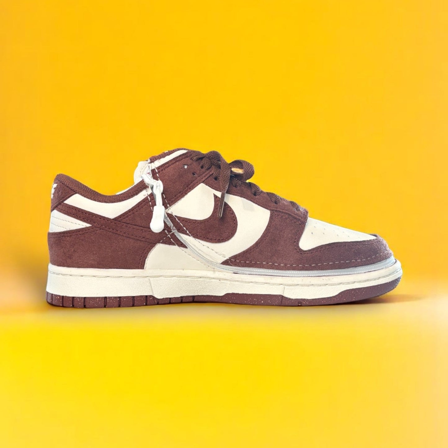 Maroon and white shoe with a zipper on yellow background. The shoe is zipped shut