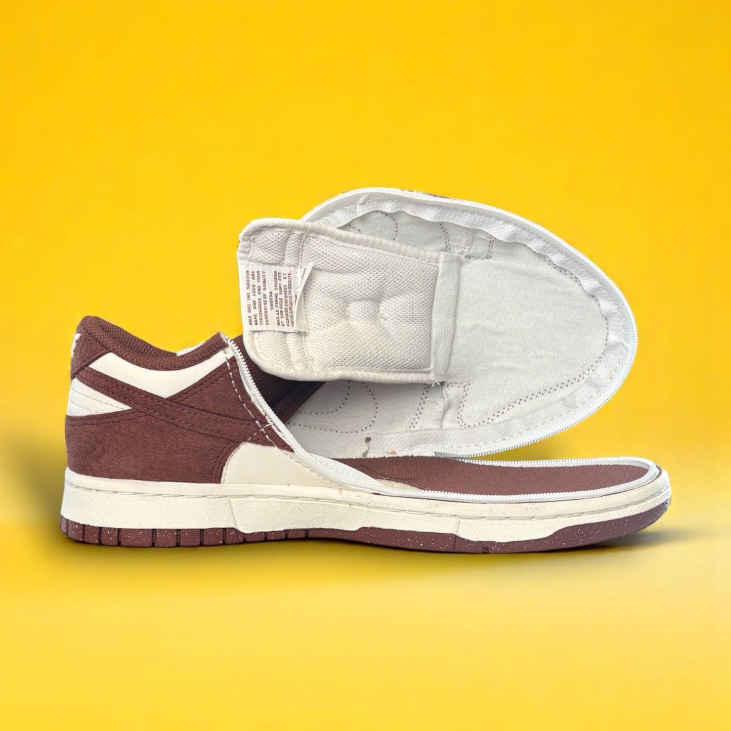 Maroon and white shoe with a zipper on yellow background. The shoe is fully open