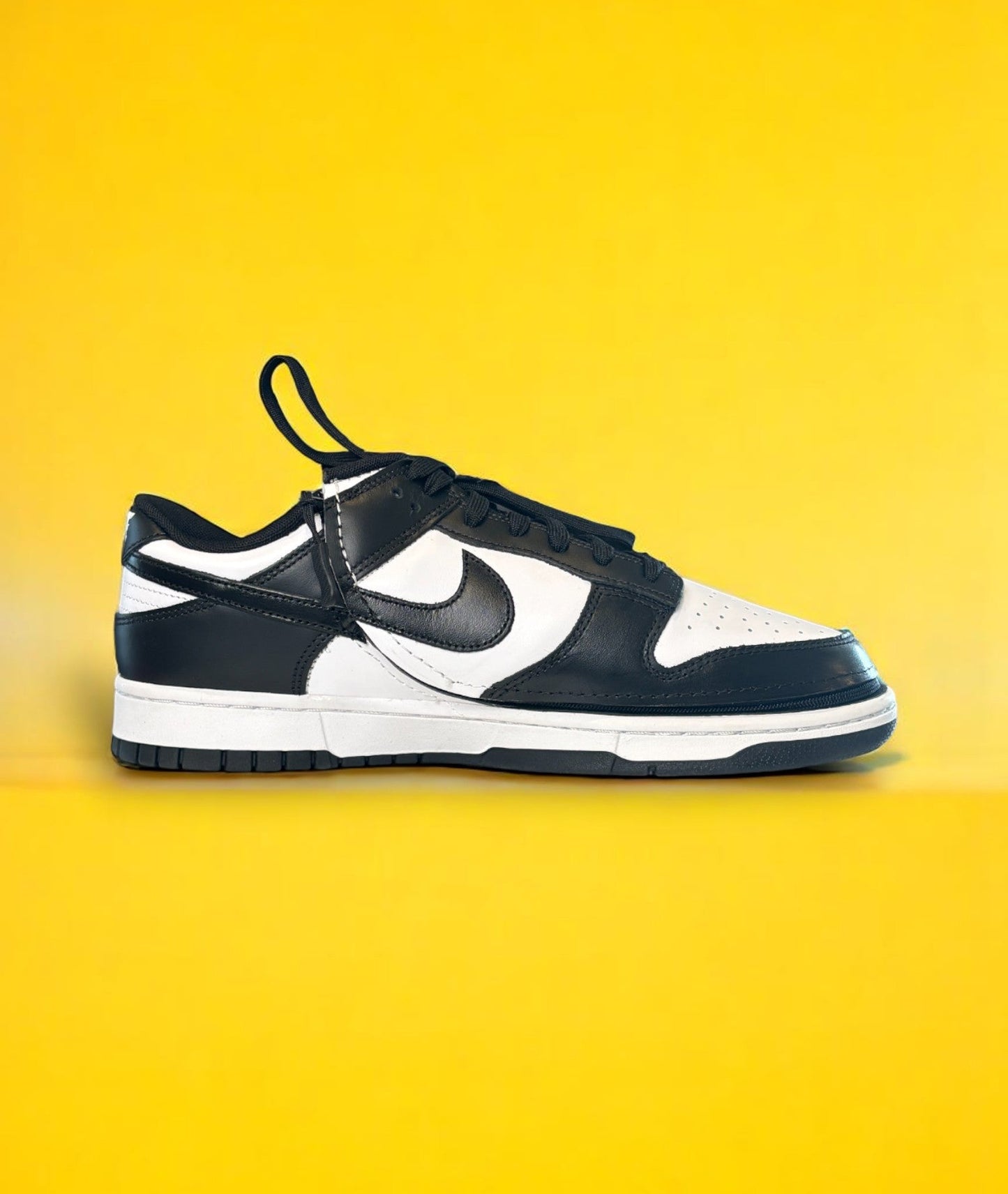 Black and white dunk low retro shoe with a zipper on a yellow background. The shoe is zipped shut