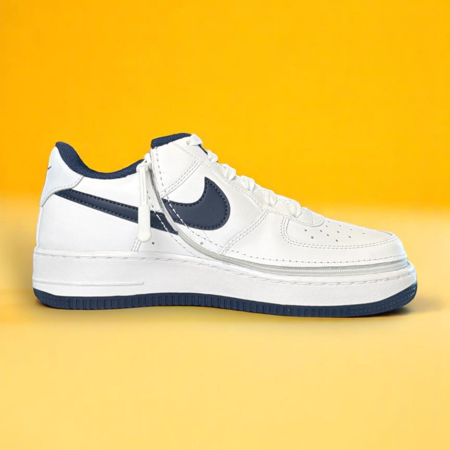 Kids white and navy shoe with a zipper on yellow background. The shoe is zipped shut