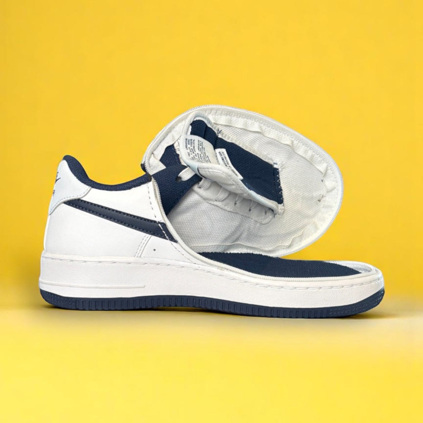Kids white and navy shoe with a zipper on yellow background. The shoe is fully open
