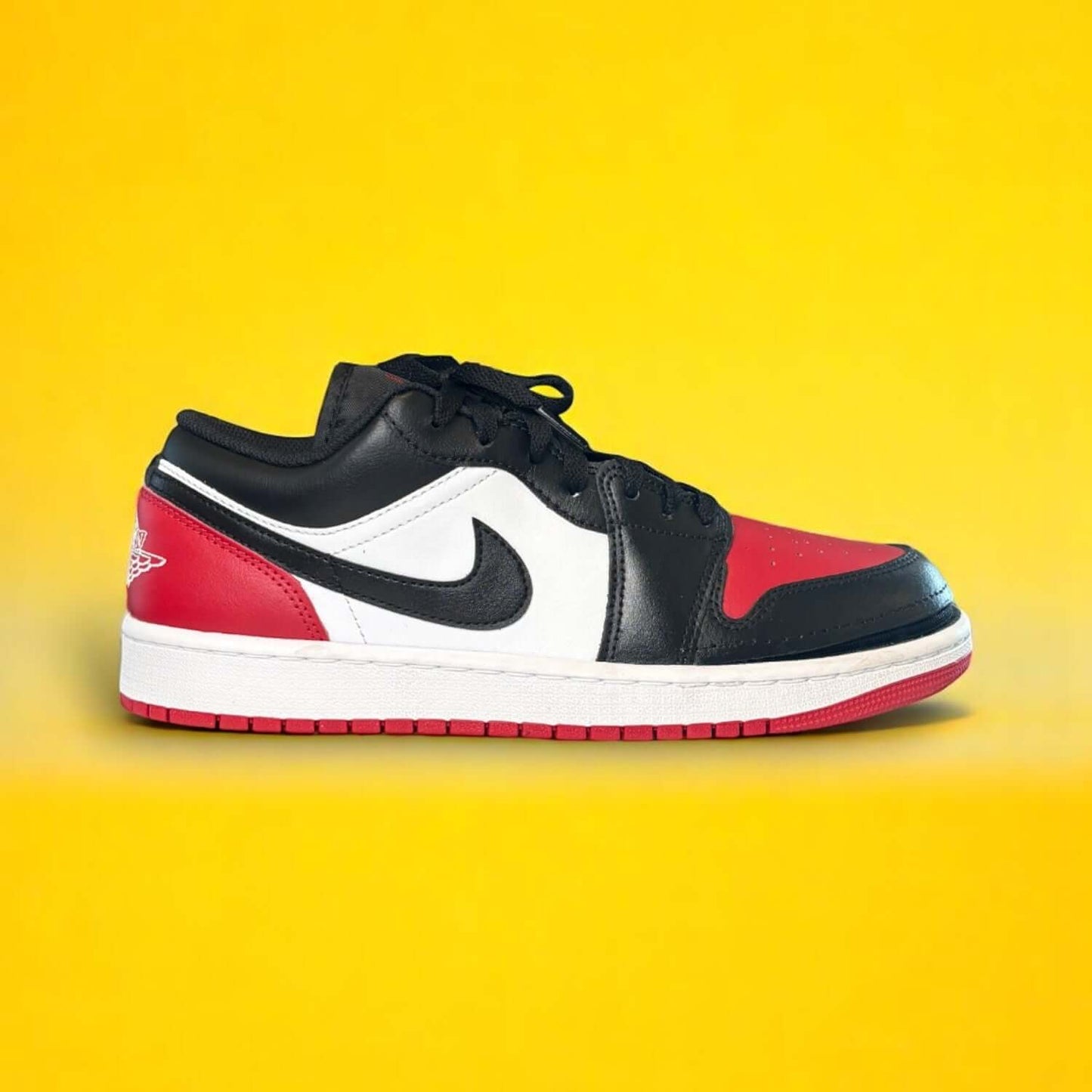 Black, white, and red shoe with a zipper on a yellow background
