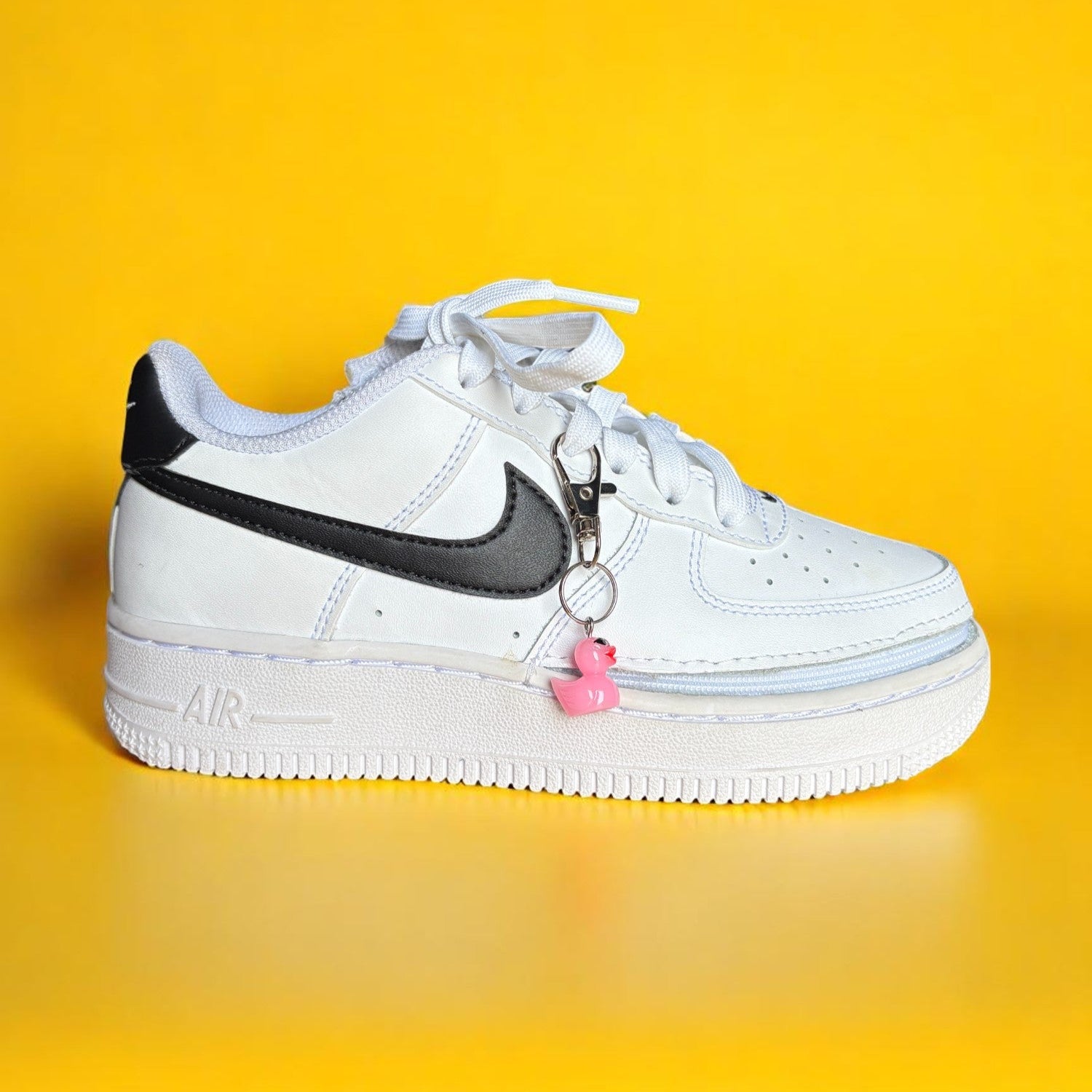 White sneaker with black swoosh logo on a yellow background