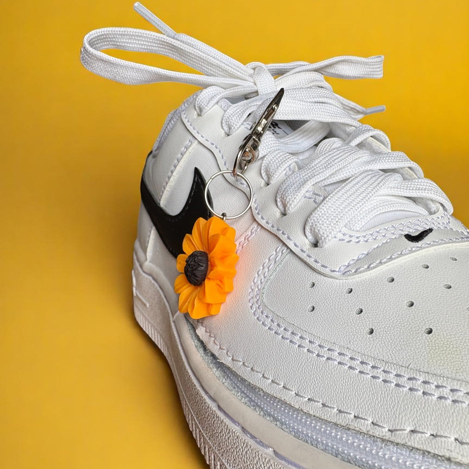 White sneaker with a sunflower charm on a yellow background