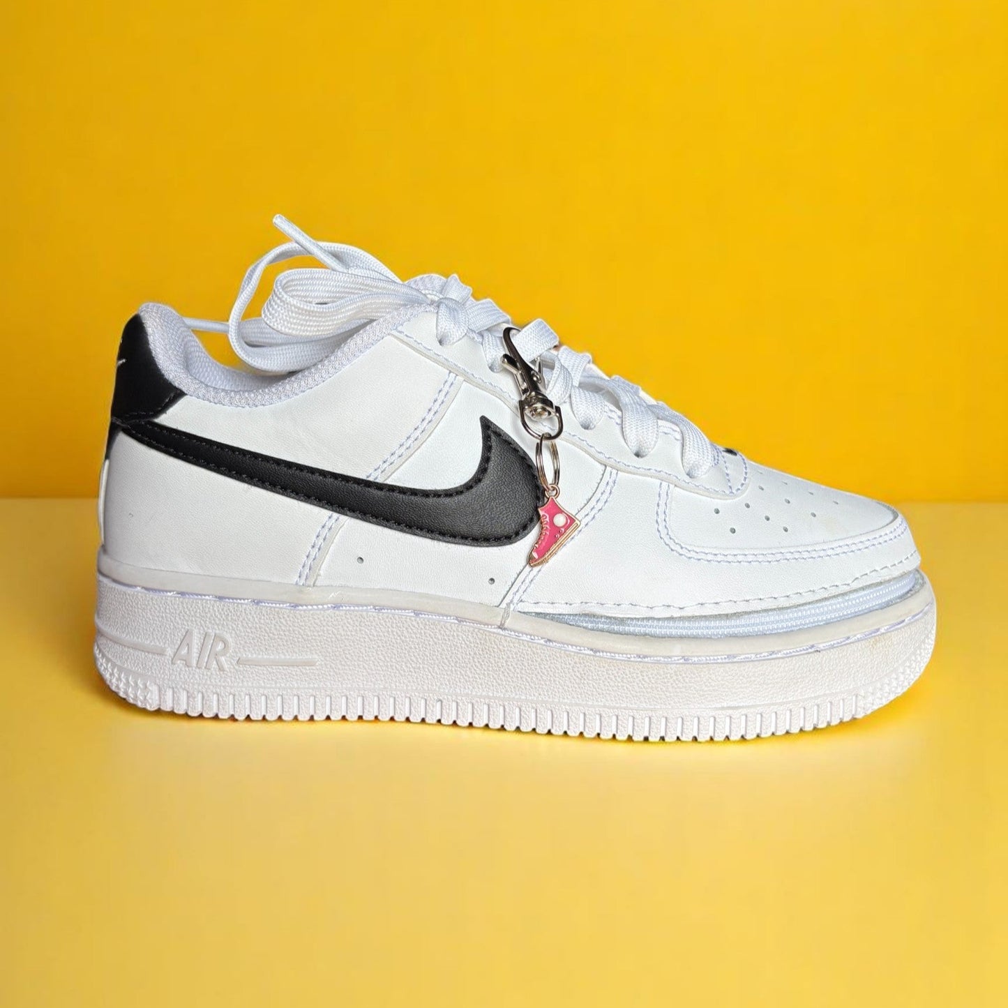 White sneaker with black swoosh logo on a yellow background