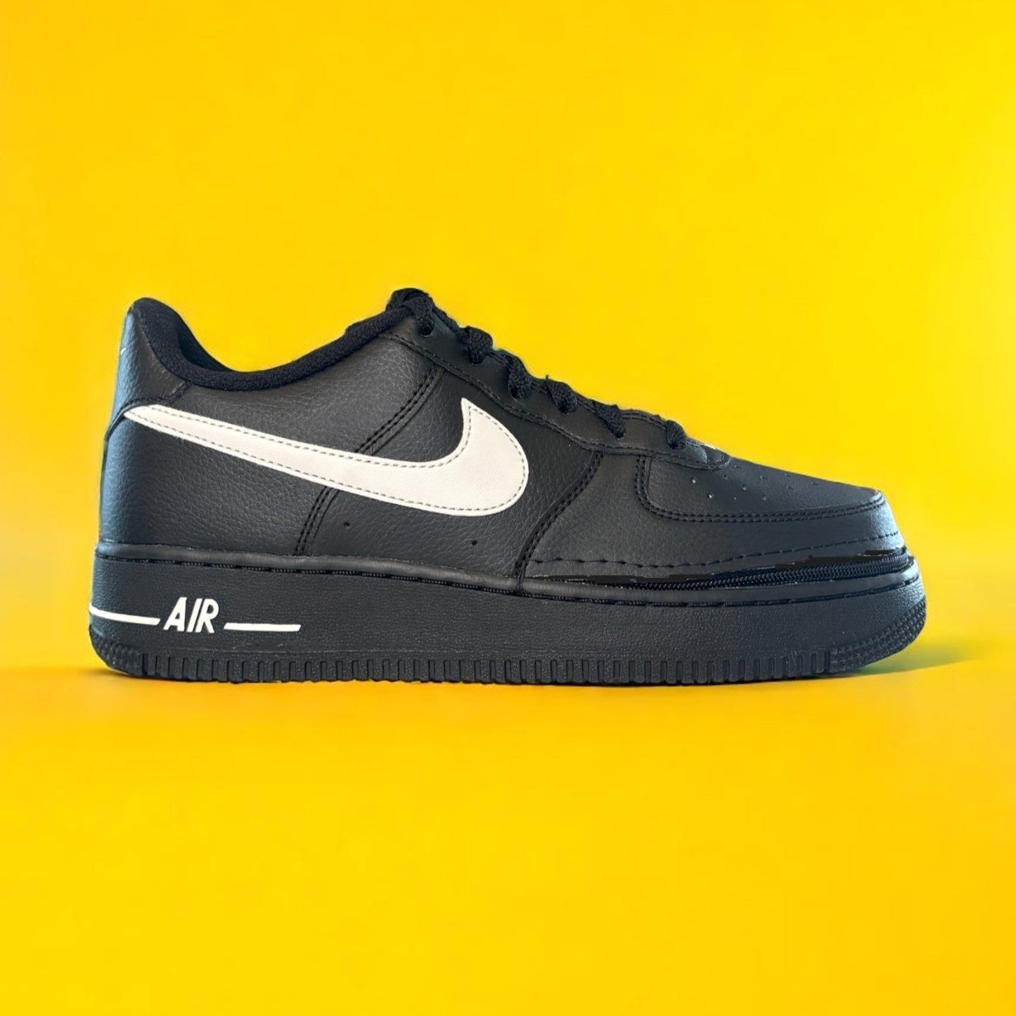 Kids black Nike shoe with a zipper on yellow background. The shoe is zipped shut