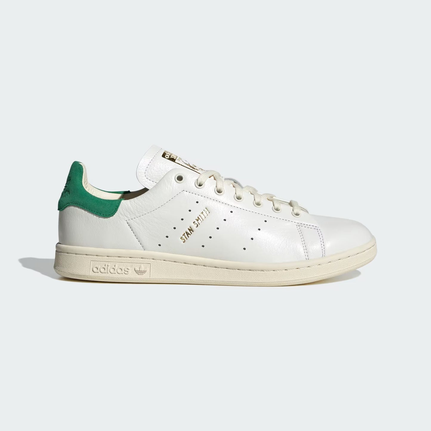 White sneaker with green heel on a light gray background