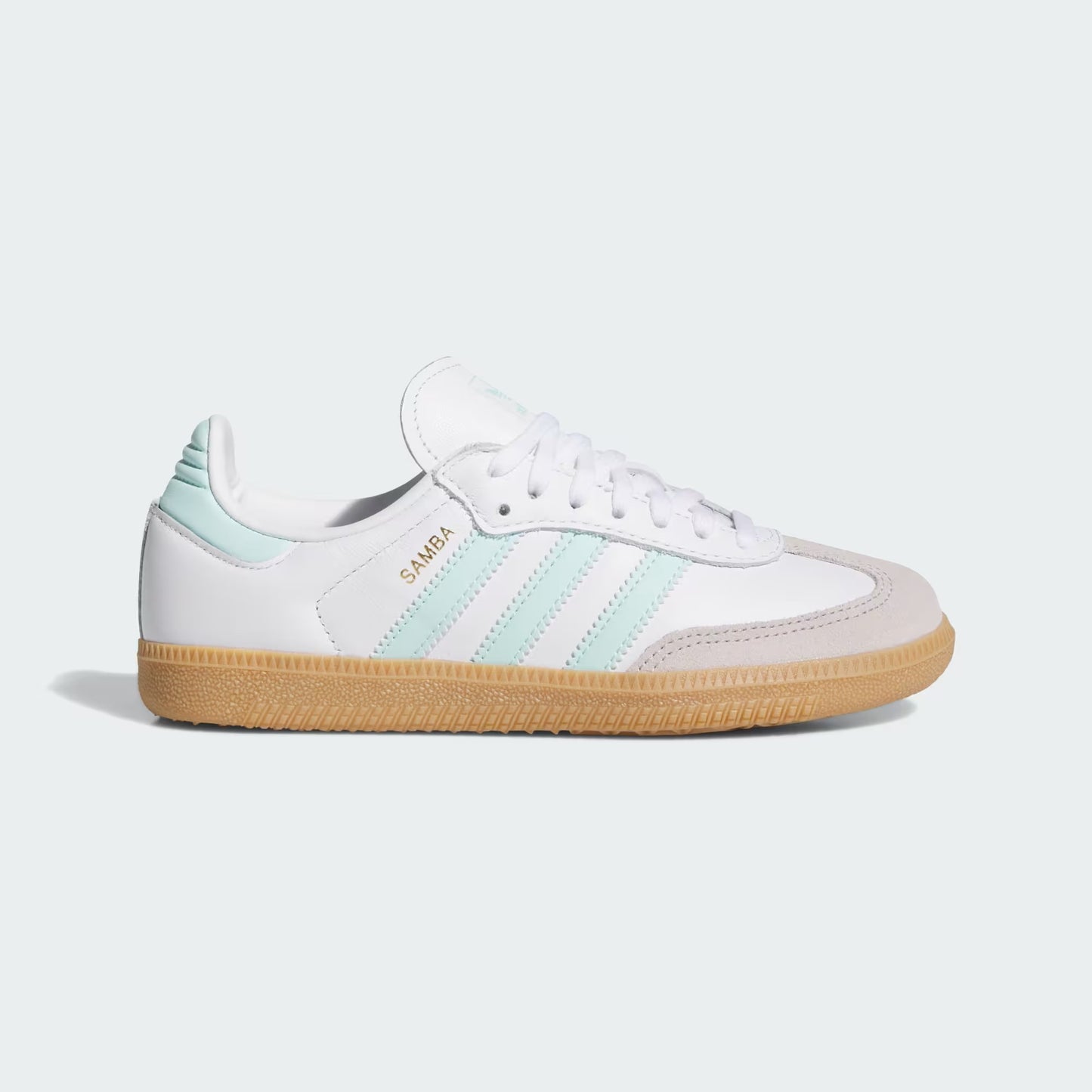 White sneaker with green stripes and brown sole on a light gray background