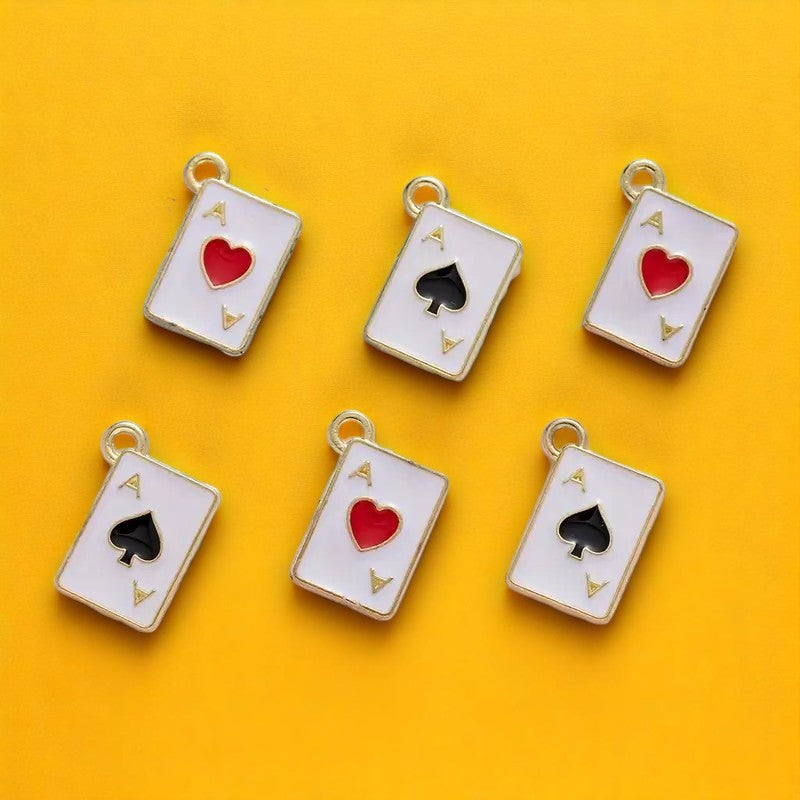 Six charm pendants designed to look like playing card aces in different suits, with red, black, and gold colors, displayed on a yellow background.
