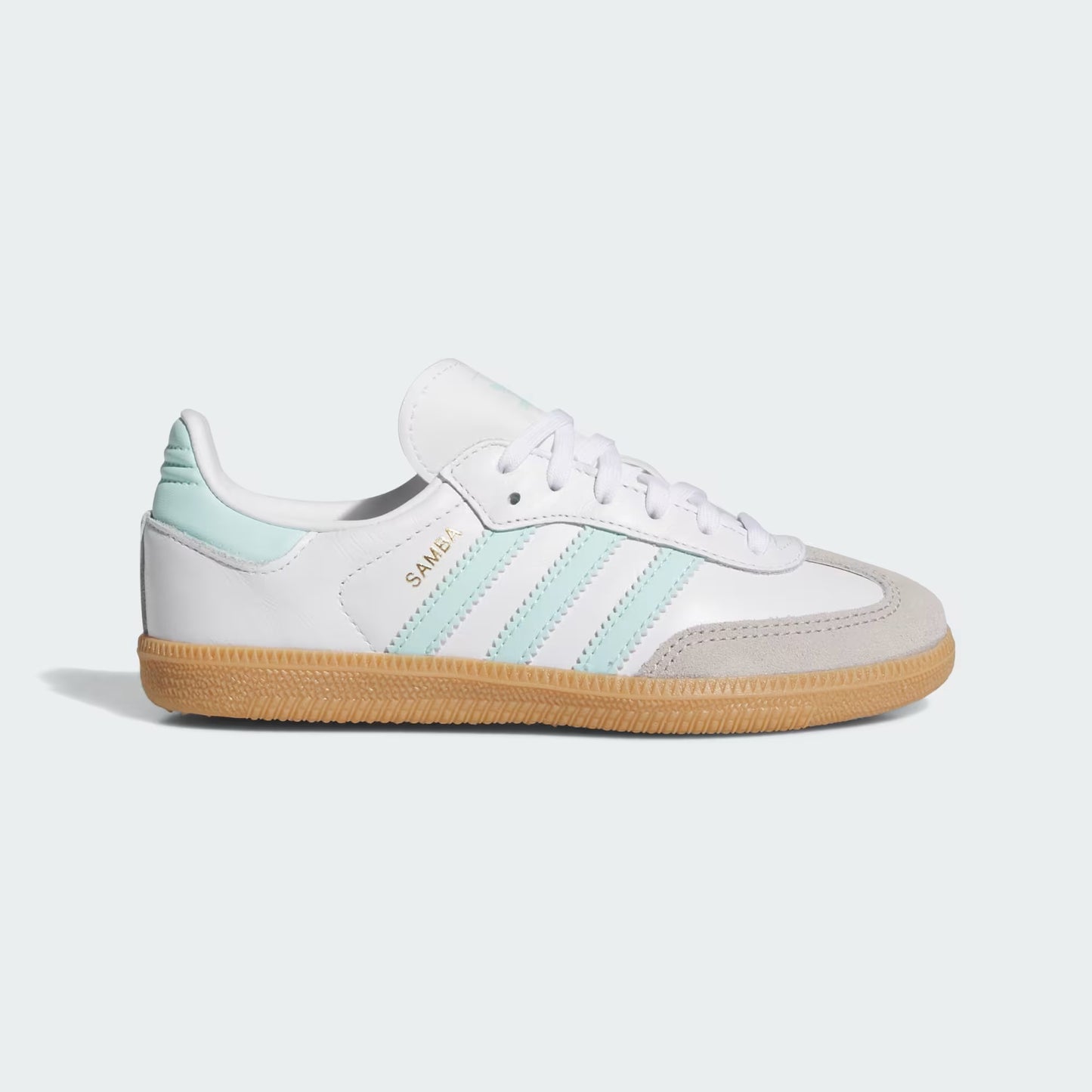 White sneaker with green stripes and brown sole on a light gray background